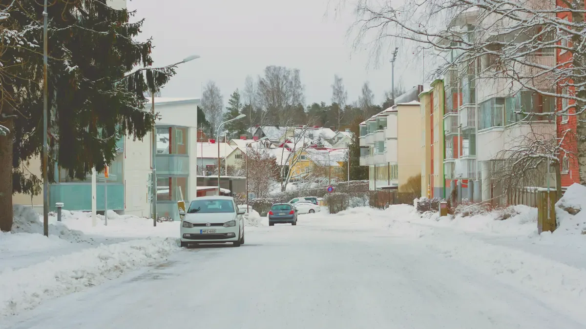 Snötäckt bostadsgata med parkerade bilar